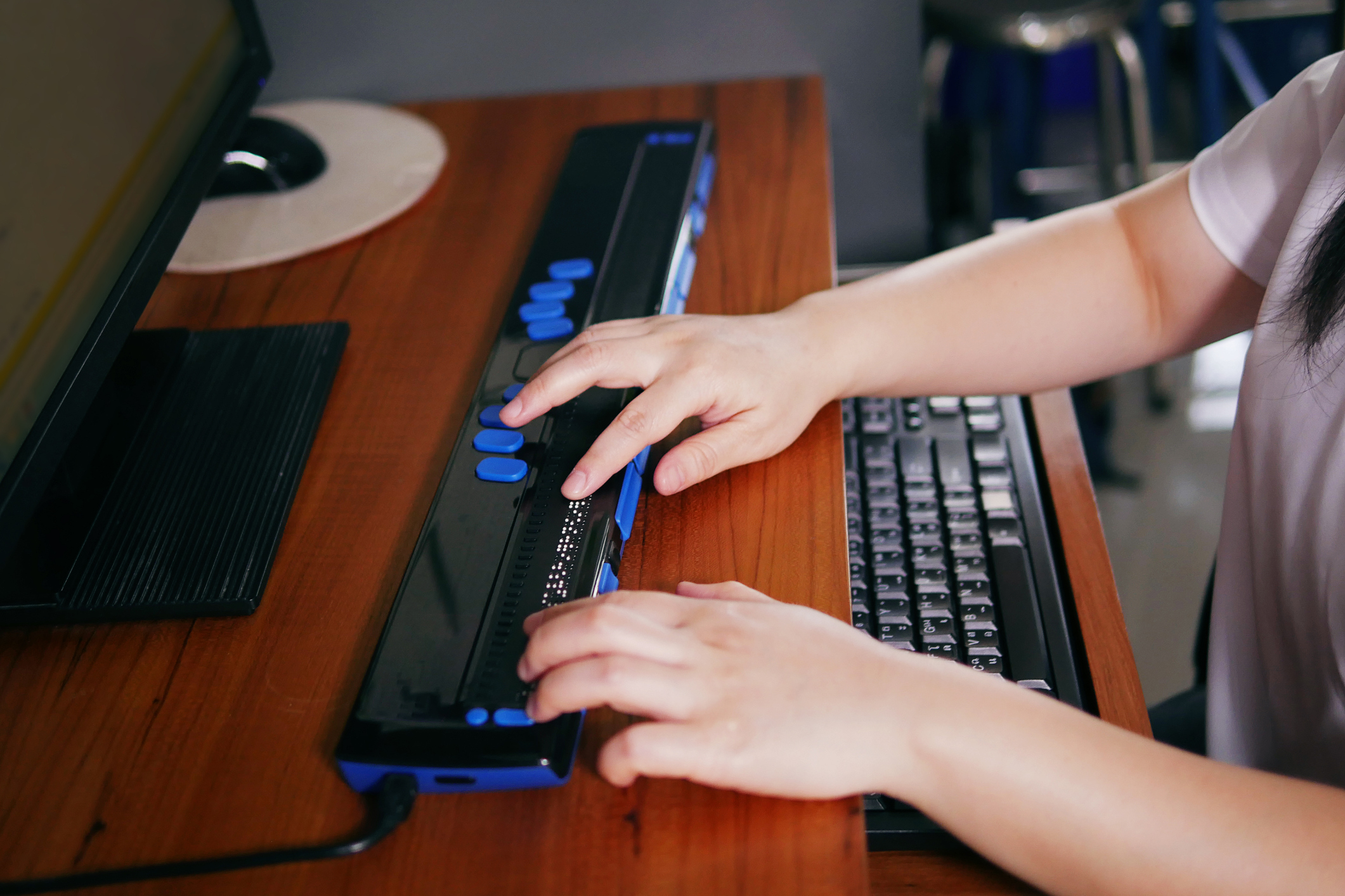 Person with blindness disability's hands using computer with braille display or braille terminal a technology assistive device for persons with visual impairment.